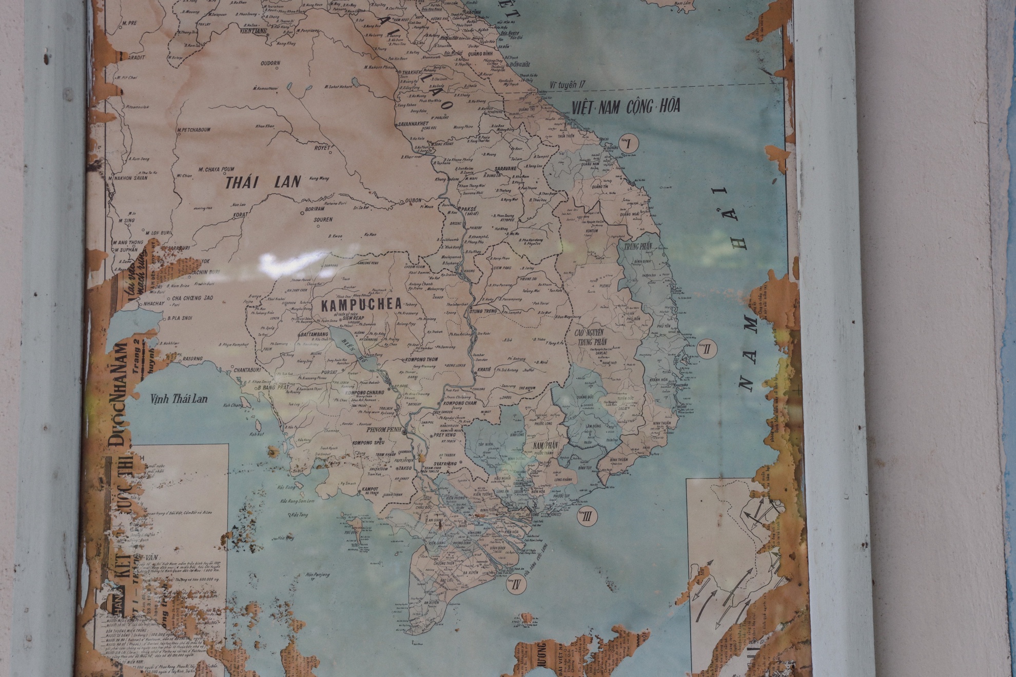 A pre-1975 map of Vietnam under glass, torn at the edges and backed with newspaper.